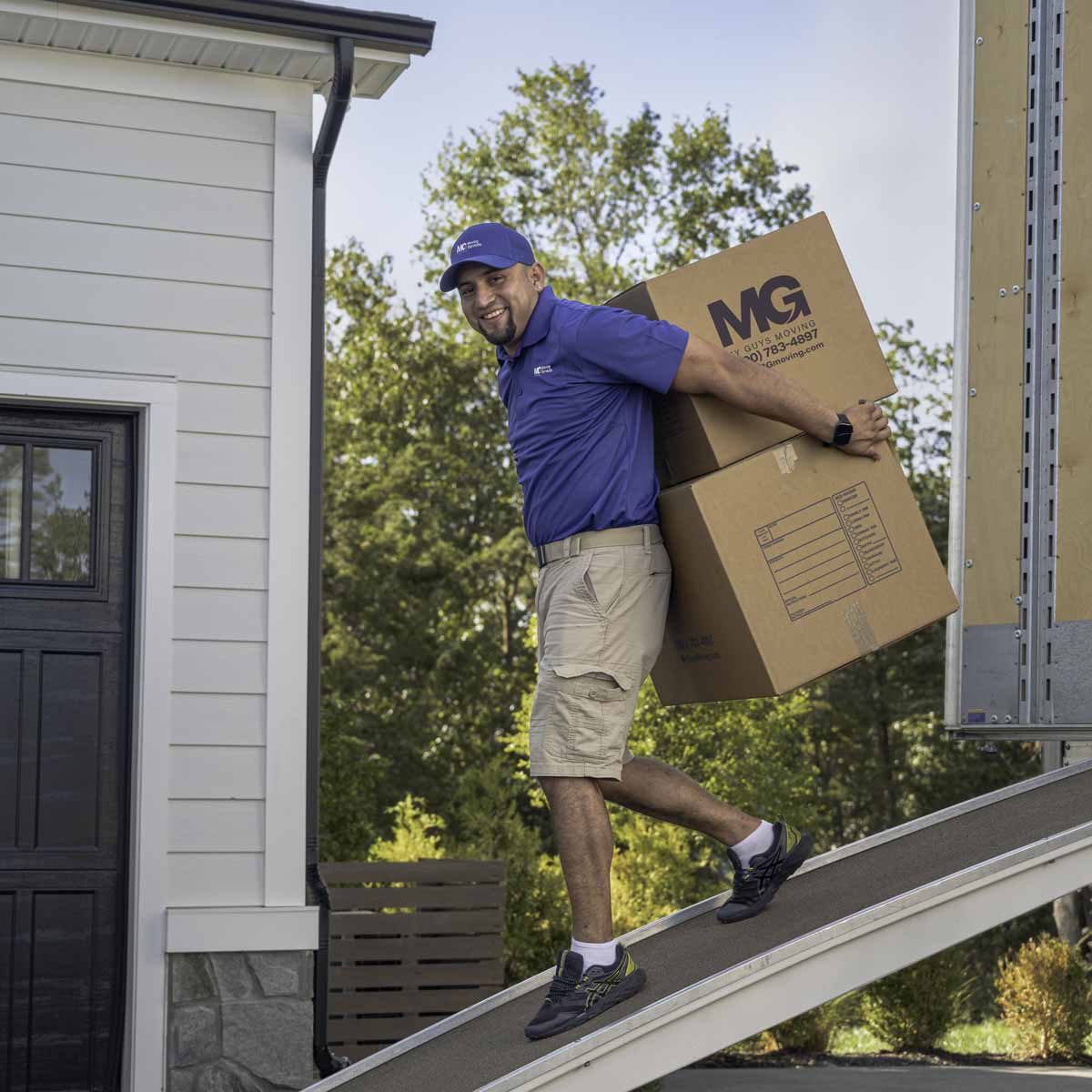 MG Moving team member carrying boxes down a ramp