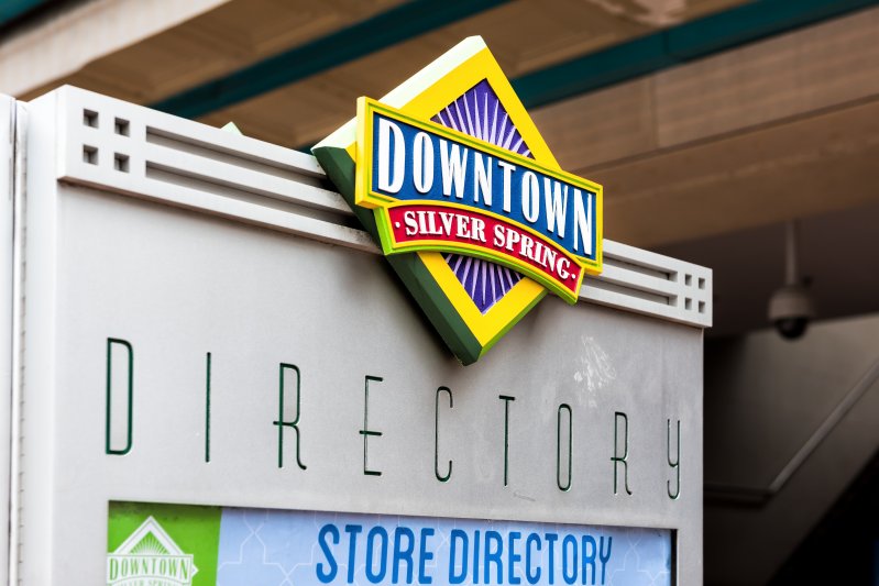 Downtown area of city in Maryland with closeup of large sign on shopping mall building and directions for restaurants and shops